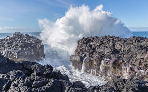 waves breaking or crashing into rocky coastline creating water spray mist