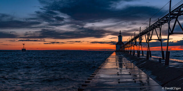 a pier and lighthouse with sunset cloudscape