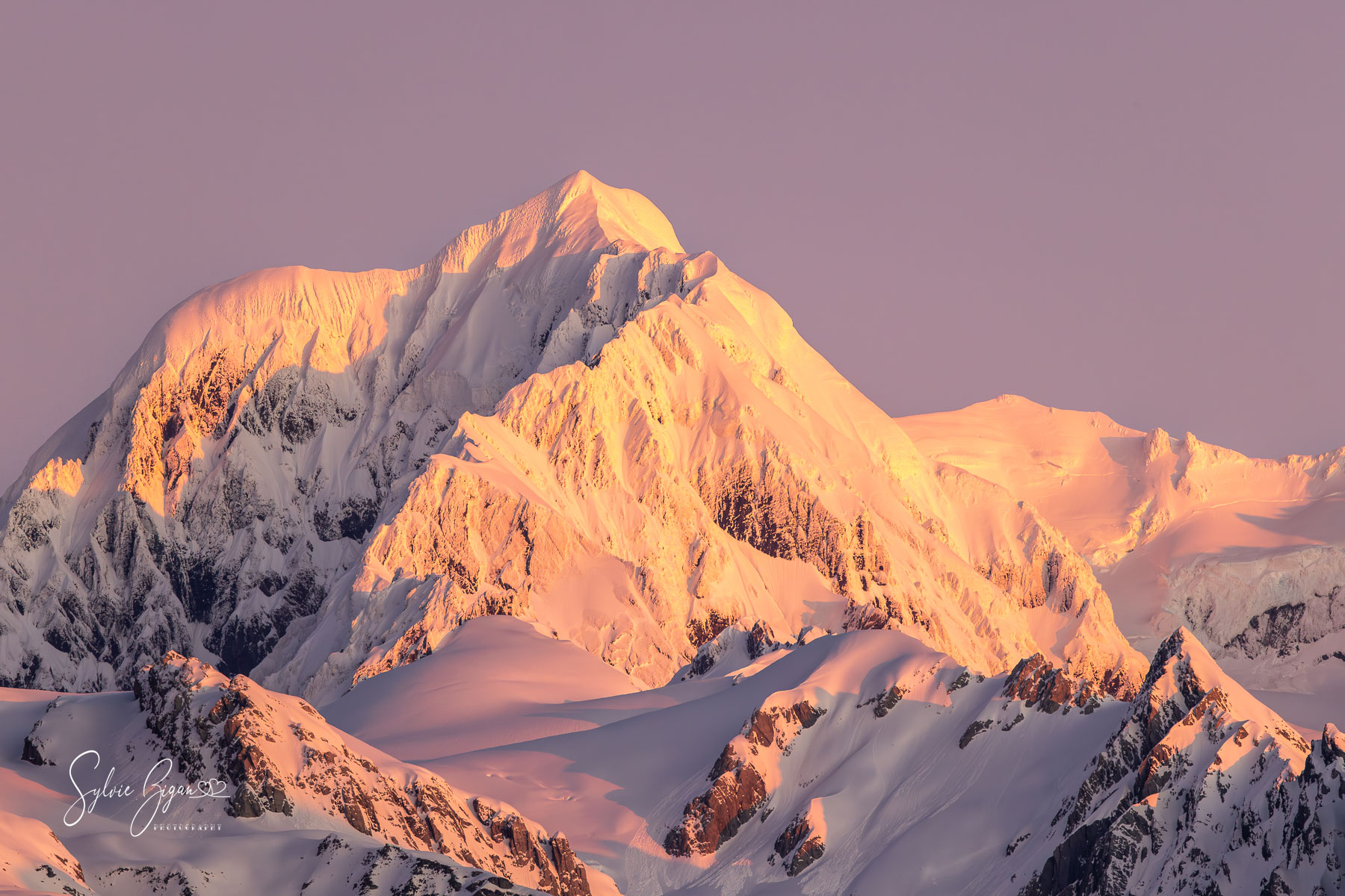 Blush of the Sacred Peak sunset on snow-capped mountain peak