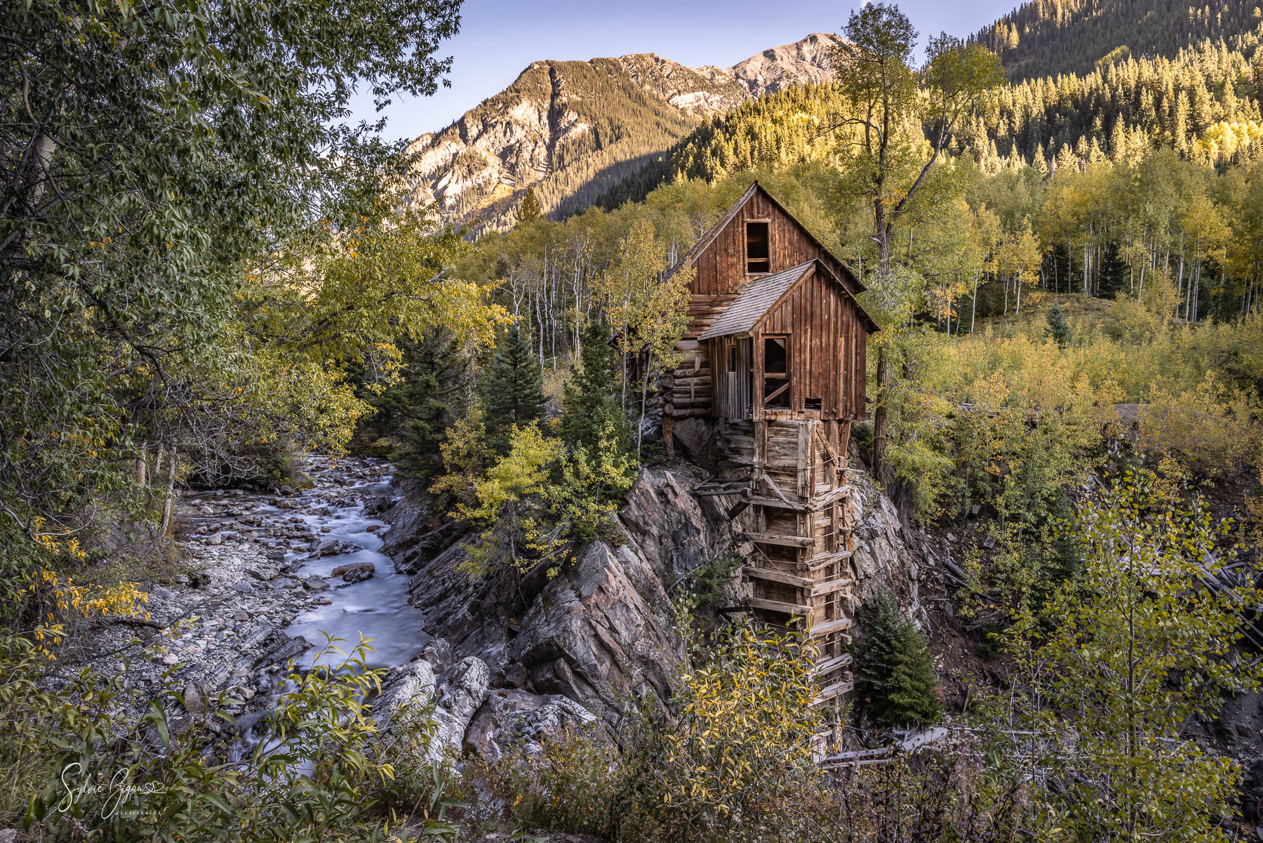 Quiet Witness to Fall old building in a mountain valley with a stream