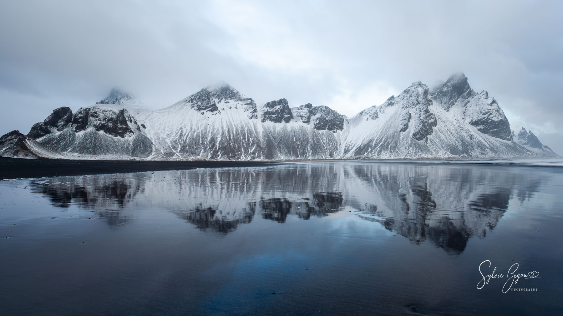 Guardians of the glass sea panoramic winter scene of snow-covered mountains on a wet beach